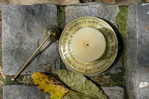 Brass candle stand with engravings on a stone surface with leaves