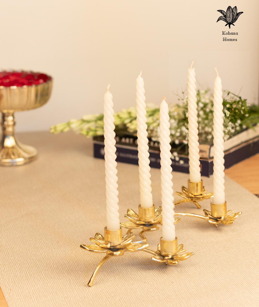 Gold candle holder with white candles on a table.