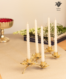 Gold candle holder with white candles on a table.