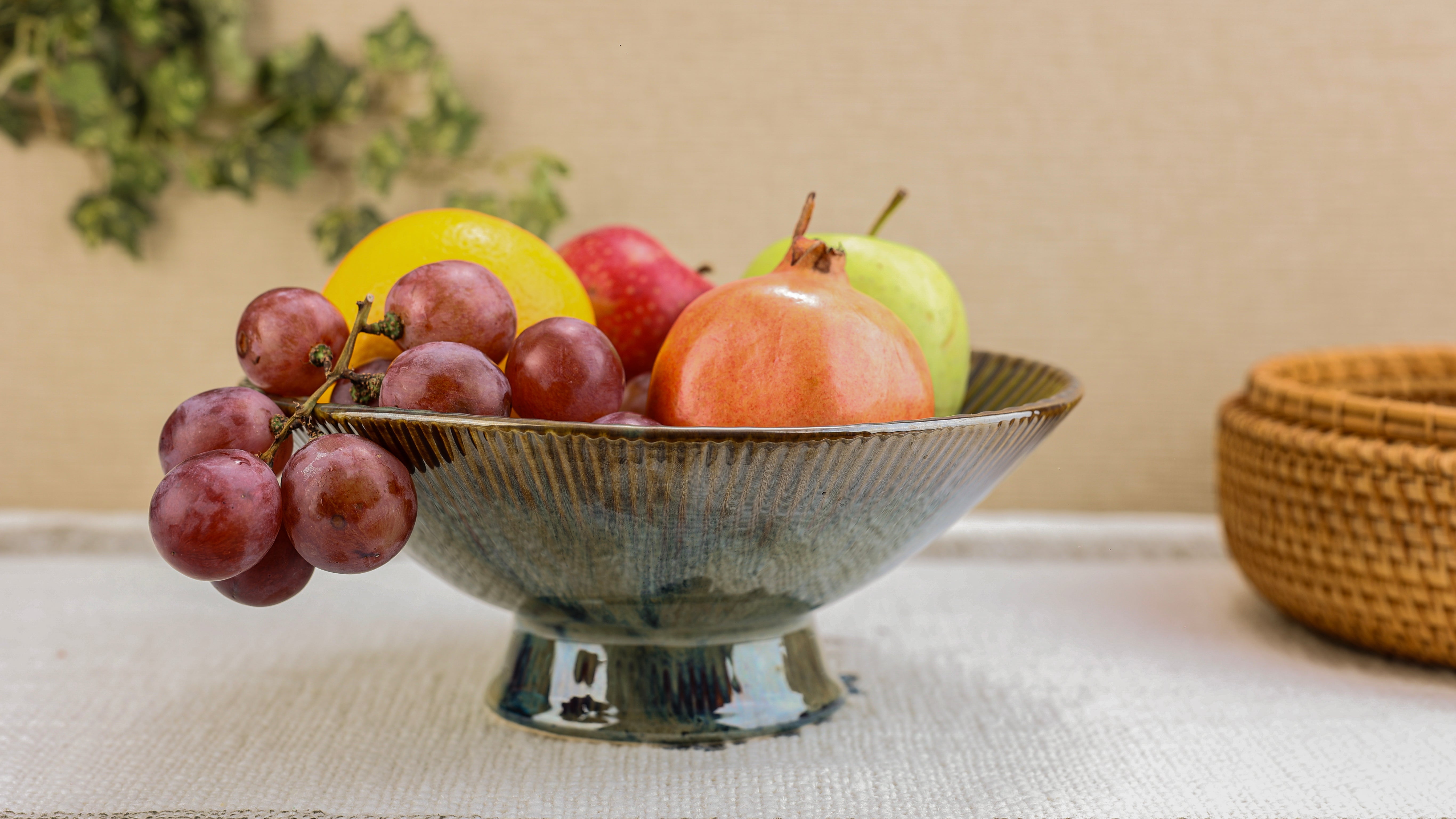 Fruit bowl with grapes, apples, and pears on a table with a neutral background